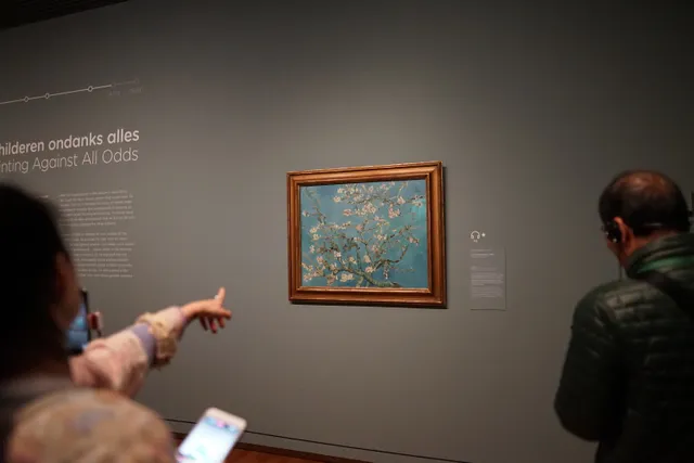 Gallery visitors viewing a painting, with a person pointing towards it
