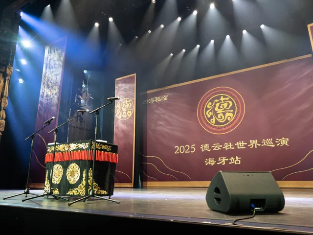 Table, microphones and tour backdrop on the Deyunshe stage in The Hague